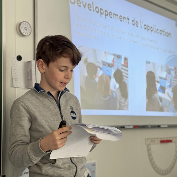 Un élève de 6e année présentant son projet devant un tableau interactif.