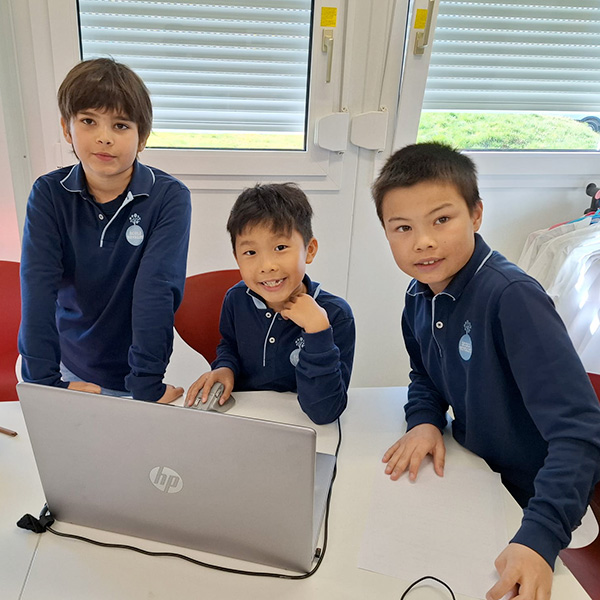 Trois élèves de l’école Vivalys réunis autour d’un ordinateur portable pour résoudre un défi mathématique.